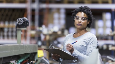 Mid adult, African American woman (30s) working in manufacturing facility.
