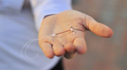 Holding an IUD birth control device in hand