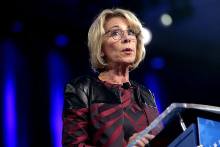 IMAGE: Education Secretary Betsy DeVos stands at a podium saying things that probably aren't true to the crowd gathered at CPAC in February, 2017.