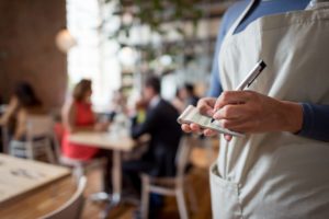 Close-up on a server working in a restuarant and holding a notepad