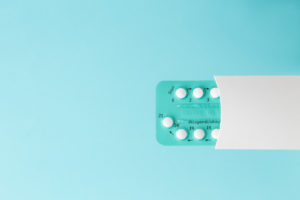 Pack of oral contraceptive pills with instructions. Blister in white case on blue background