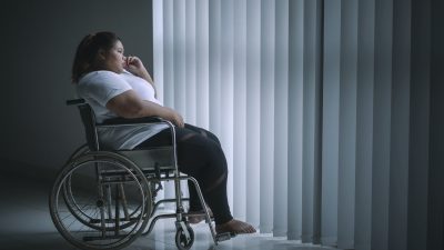 Disabled woman looks pensive near the window
