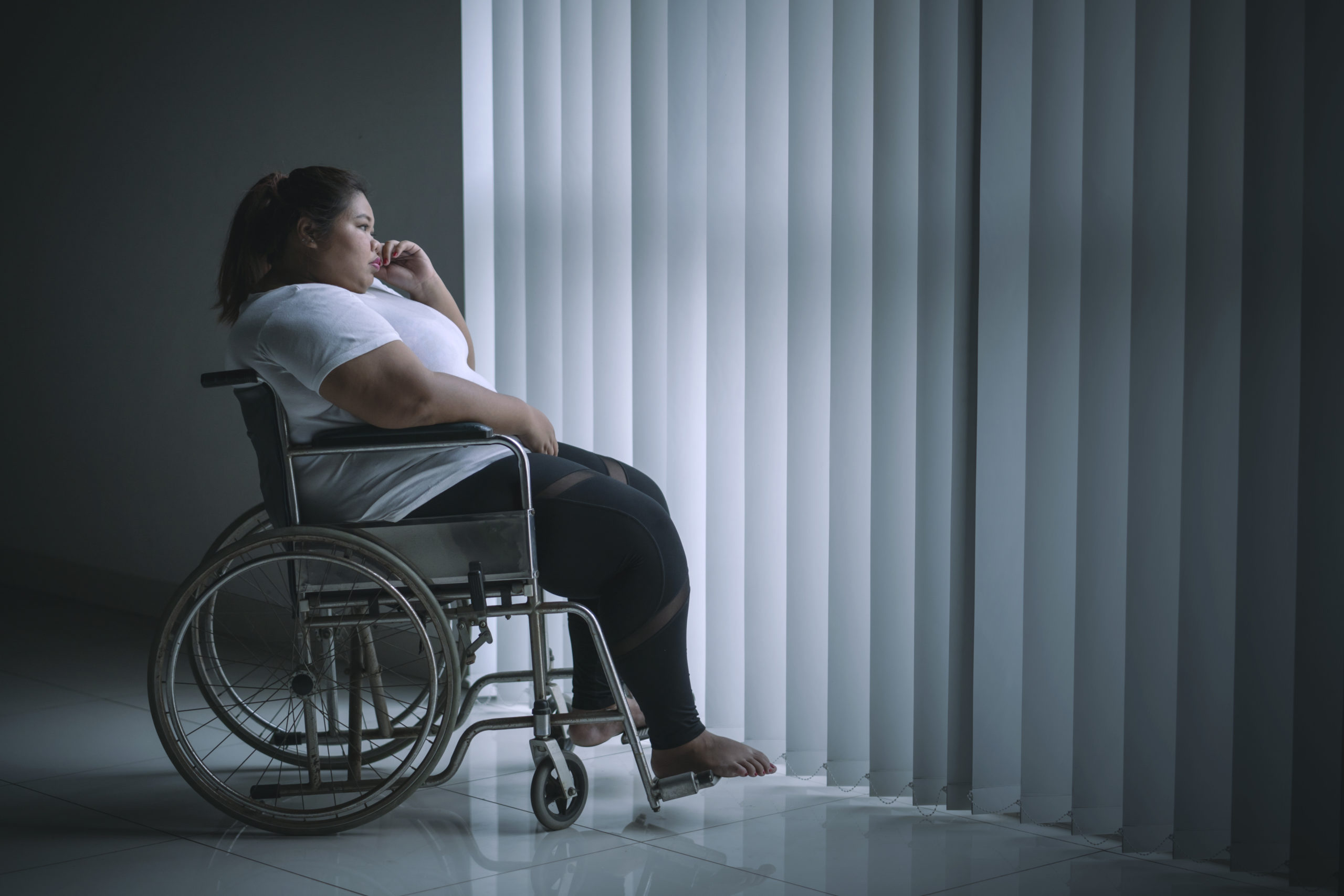 Disabled woman looks pensive near the window