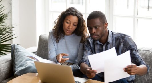 Serious African American couple discussing paper documents,