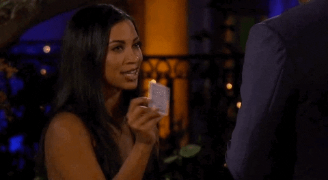 Bachelor contestant holding up a playing card with a V on it