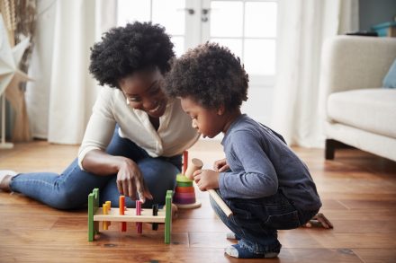 Mother And Young Son Playing With Wooden Toy At Home