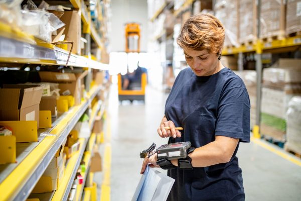 Woman in warehouse pushing buttons on wearable barcode reader
