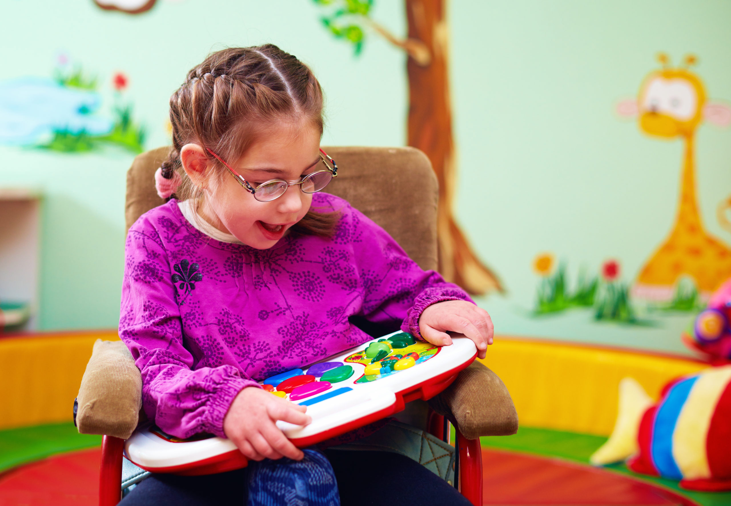cute girl in wheelchair playing with developing toy in kindergarten for children with special needs